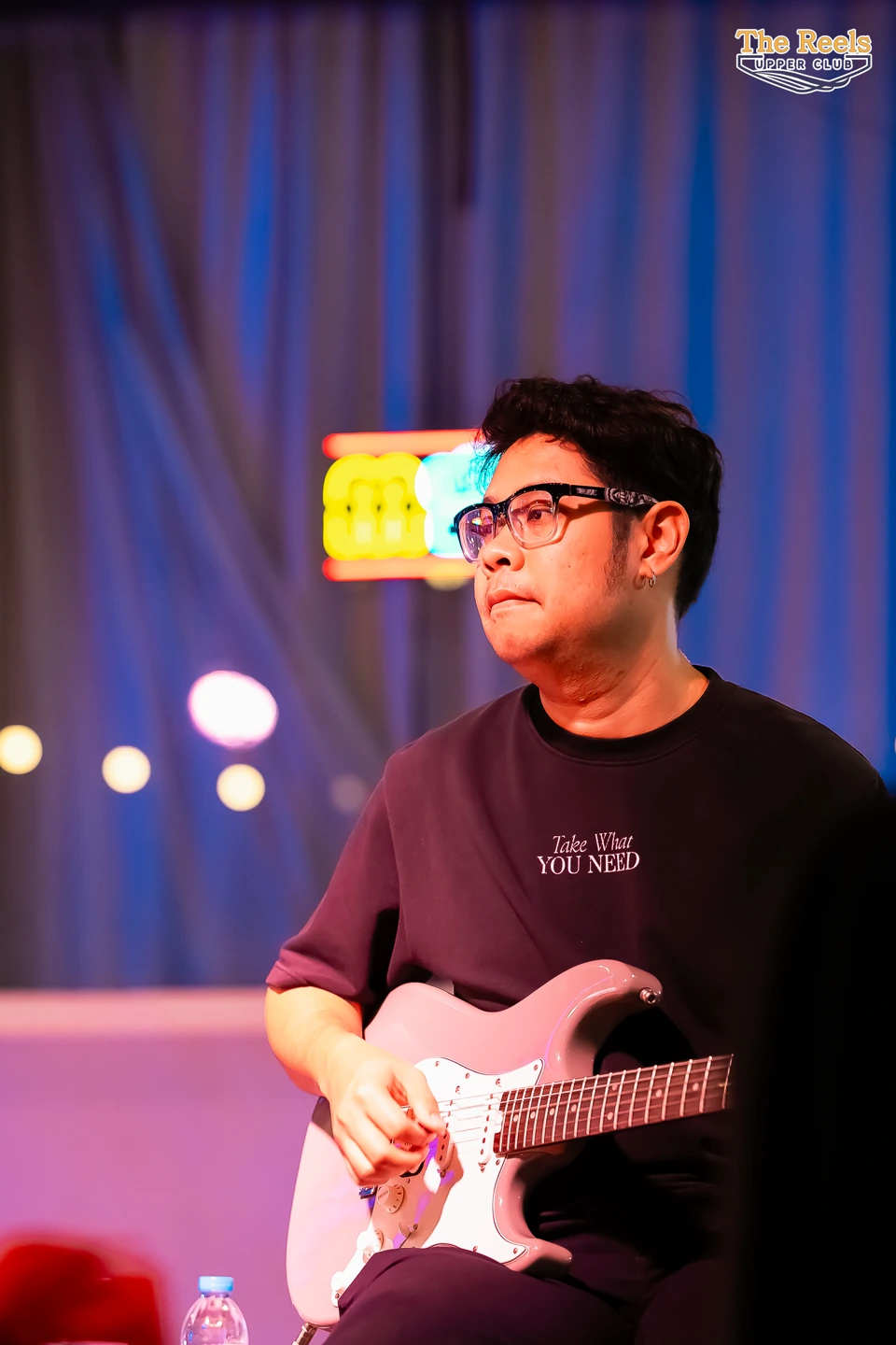 The performer on stage with an electric guitar, name withheld